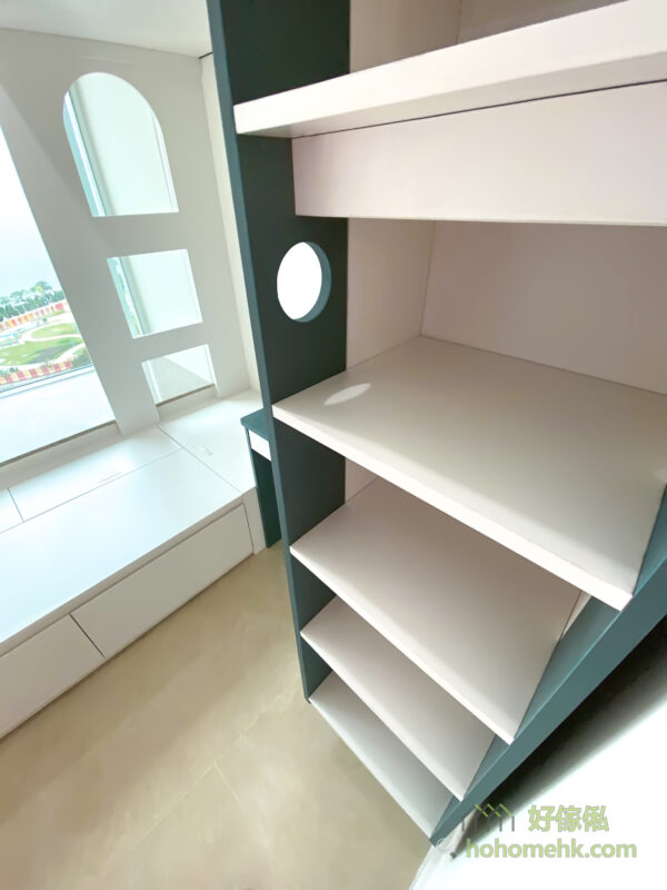 設計師將爬梯融入成為儲物櫃的一部份 —— 最前的部份是爬梯的腳踏部份、中間是開放式的儲物櫃，後方則成為側面書枱的延伸儲物空間