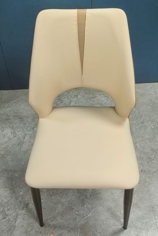 610款米白仿皮餐椅正面近照，高身靠背中央有向下收窄的雙車線裝飾，腰位設半圓鏤空，寬闊座面下方配兩隻可見的深色金屬腳。