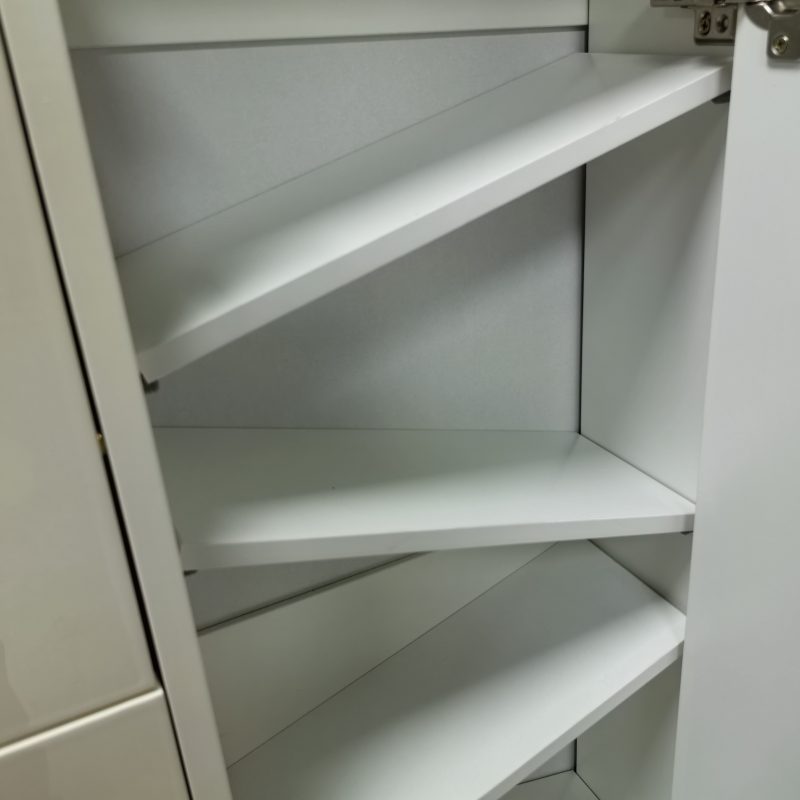 Caleb超薄鞋櫃內部特寫，白色斜板一層層向上斜疊做鞋位間隔，右側可見金屬門鉸，櫃身用亮光米白飾面，層板顏色純白帶啞面質感。