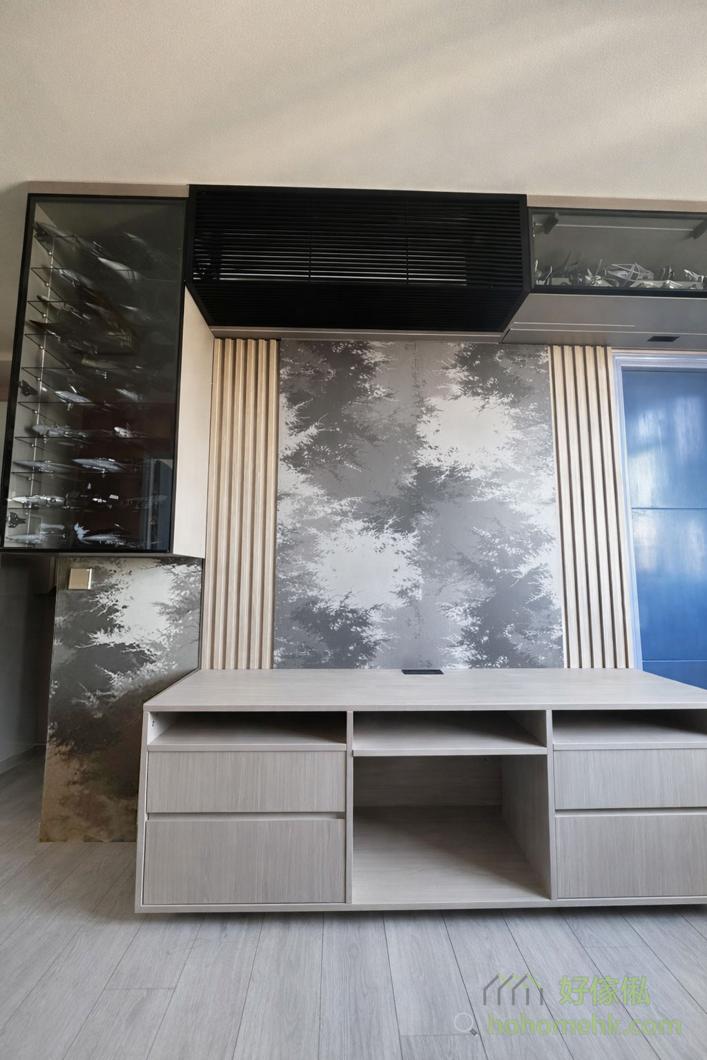 暮色系的電視櫃設計以深色為主，背板運用了「月影」色板，增添了一種神秘優雅的氛圍。這種設計與客戶原有的玻璃飾櫃完美融合，既保留了整體空間的和諧美感，又突出了訂造傢俬的獨特風格，是現代型格家居的理想選擇。