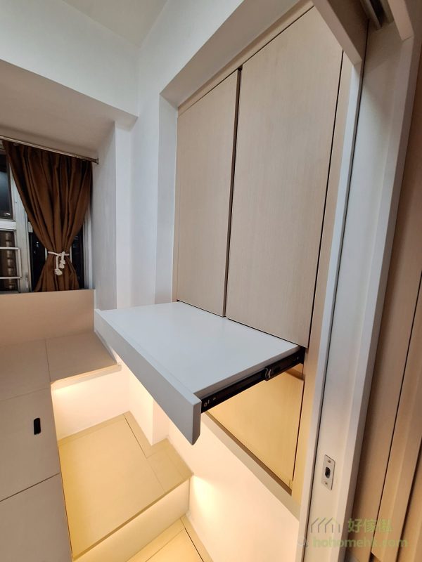 衣櫃內隱藏了一張小小的拉出式枱，簡單而實用，可以作為梳妝枱或摺衫枱使用。這種隱藏式設計不但不佔空間，還提升了家具的靈活性，充分滿足日常生活需求，為小戶型住戶帶來更多便利。