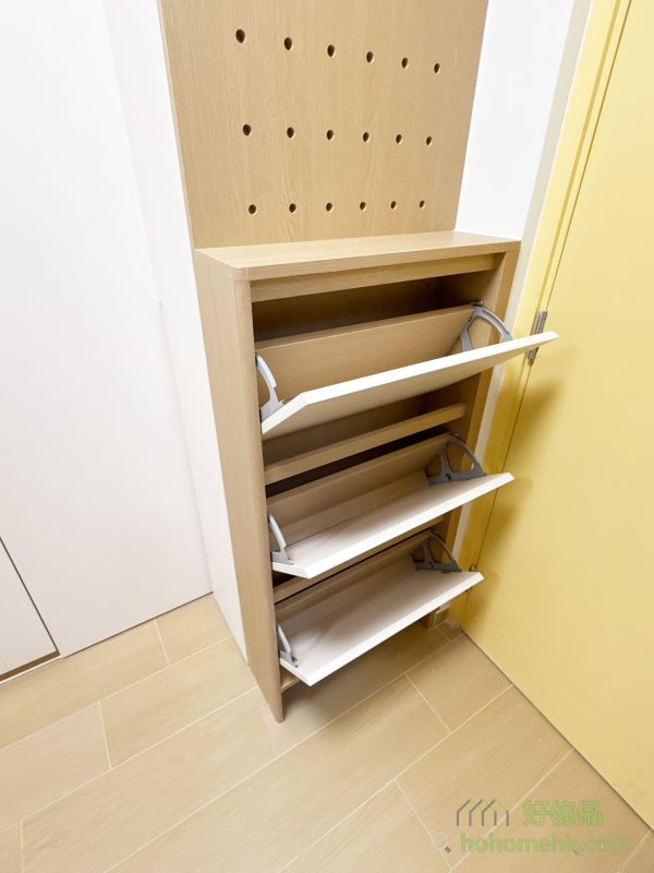 間房對面，在入門旁訂造了一個小鞋櫃，善用空間設置多功能收納區，翻摺式鞋櫃既能節省地面空間，又便於日常生活取用。而枱面就手的高度亦方便放置信件和鎖匙等小物件，而上方更訂造了同色洞洞板，掛外套、手袋，甚至各類飾品都OK，不論是家庭雜物、鞋類或小型飾品，都能找到專屬的收納位置，保持客廳與間房的整潔與條理。