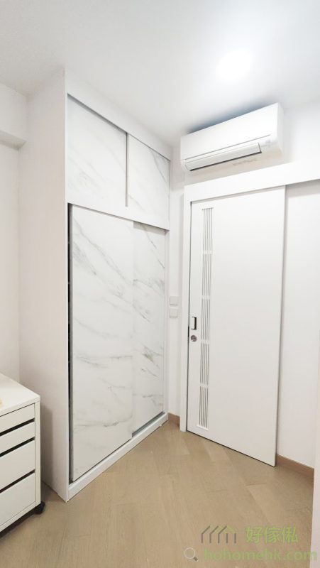 房內的衣櫃亦沿用電視櫃及背景牆的板材及紋理，確保全屋設計風格一致。大理石紋的衣櫃簡約時尚，實用之餘更顯生活品味。這種設計不僅耐看，亦符合現代人對簡約生活的追求。